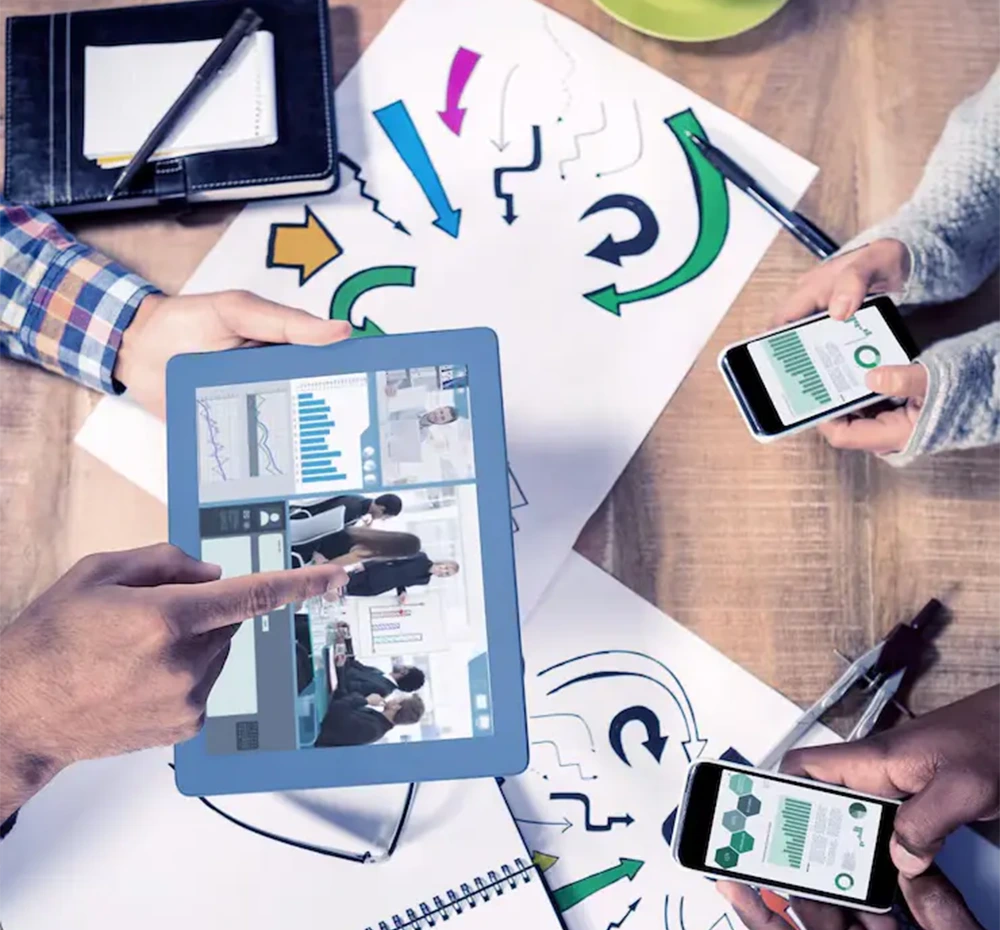 Individuals using tablets and phones, representing teamwork in a web designing company 